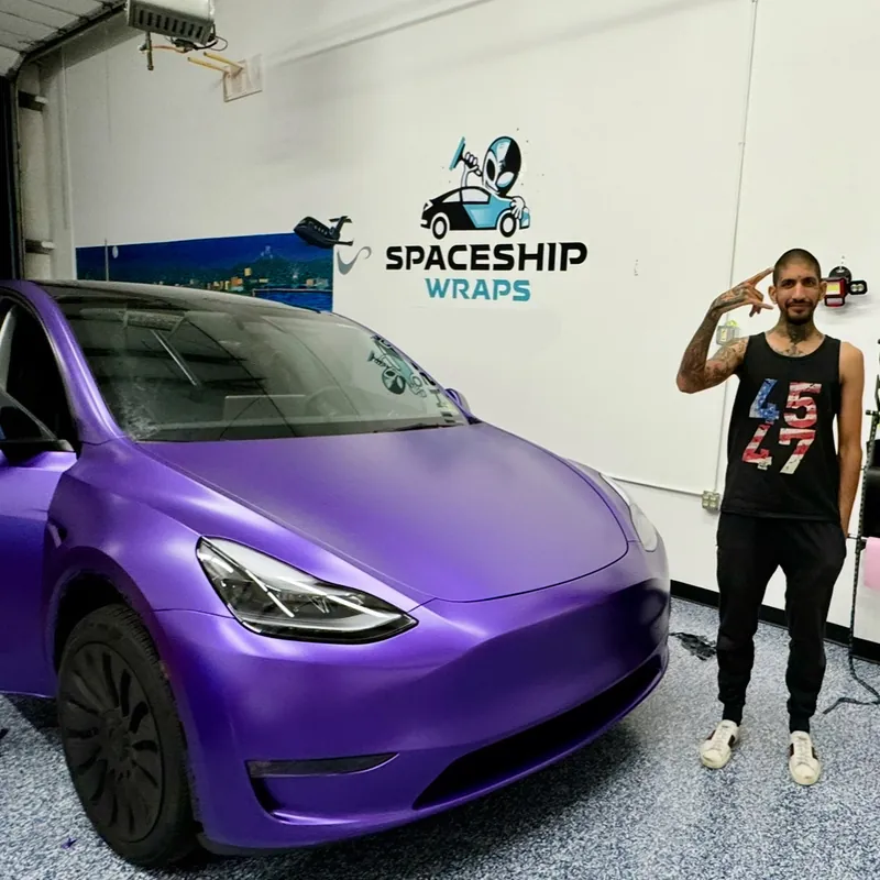 Raoul Shah beside a Tesla Model Y wrapped in purple, under the SpaceShip Wraps sign